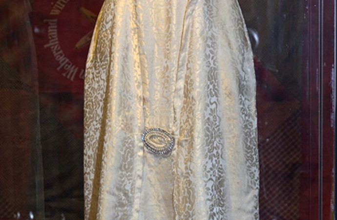 Das Foto zeigt ein champagnerfarbenes, langes Abendkleid aus Atlasseide und Seidentüll. Das Material schimmert edel. Der sogenannte Sans-Ventre-Stil b